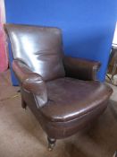 An Antique Howard Brown Leather Chair (original leather) with turned wood legs on brass castors,