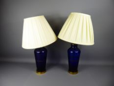 A Pair of Bristol Blue Glass and Brass Lamp Bases with cream shades, approx 41 cms high.