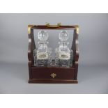 A Mahogany Tantalus with two crystal decanters, together with three silver plated liquor labels.