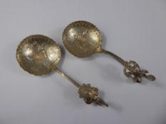 Two Continental Silver Sugar Spoons, the spoon bowls with embossed with rural domestic scenes. (2)