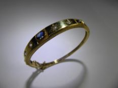 A 14ct Yellow Gold (tested) Diamond and Sapphire Bangle. The bangle with a single central oval