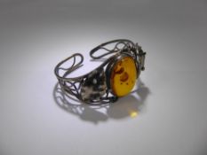 An Art Nouveau Style Silver and Amber Bangle, the yellow amber having inclusions, approx 30 x 23 mm,
