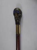 A Slim Walking Cane, the handle being a brass skull and blue glass eyes.