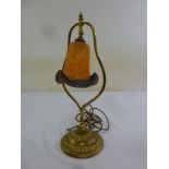 An Art Nouveau style table lamp with glass shade on raised circular brass base