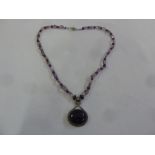 A single strand amethyst necklace with silver clasp and an amethyst cabochon pendant