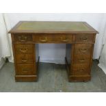 A Victorian oak kneehole desk with tooled leather top, nine drawers and brass swing handles