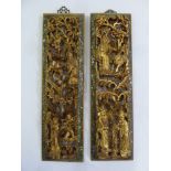 A pair of carved gilt Oriental wall panels of figures in a stylised landscape