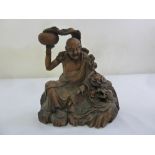 A 19th century carved Oriental wooden figurine of a elder and a dragon chasing a flaming pearl