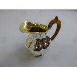 A Russian silver cream jug, lobbed baluster form with wooden scroll handle and gilt wash interior