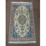 A Middle Eastern wool carpet cream ground with repeating floral design and pink floral border, 172 x