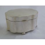 A Continental white metal shaped oval tea caddy with hinged cover on four bun feet