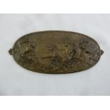 An oval bronze plaque embossed with a classical scene