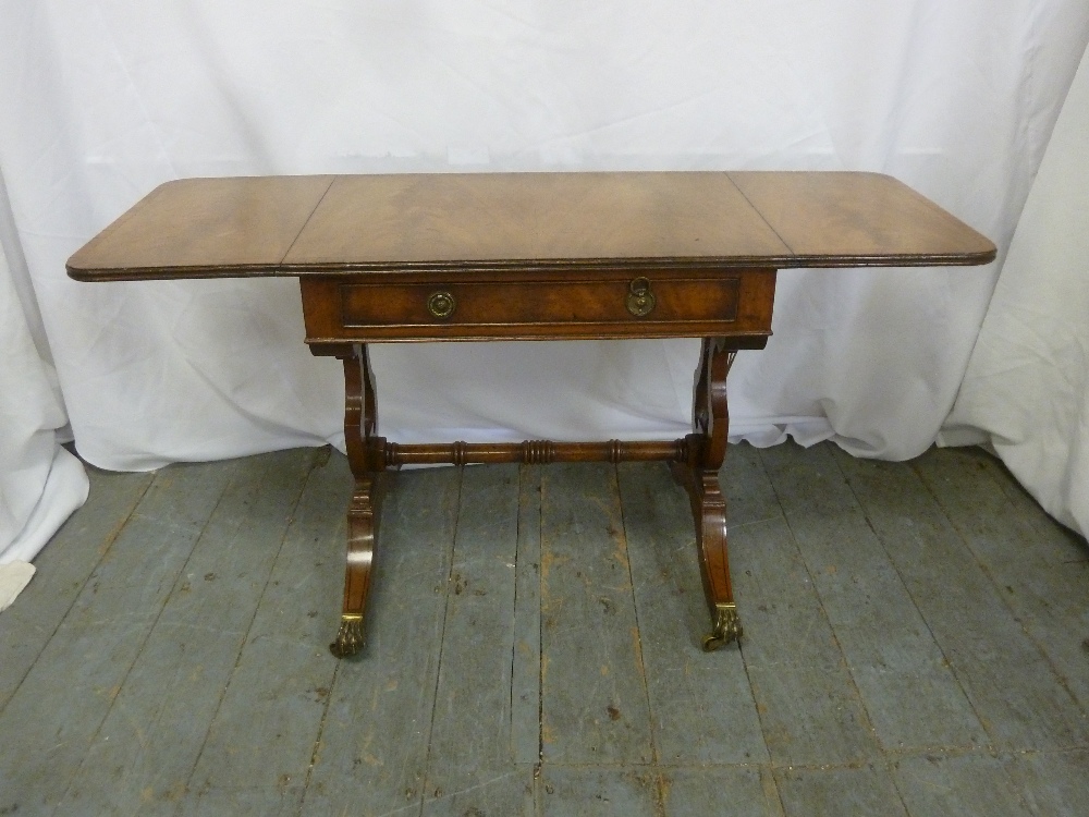 A mahogany rectangular occasional table with hinged side flaps on scroll supports with original