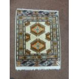 A wool prayer rug cream ground with orange and light blue pattern and border, 86 x 69cm