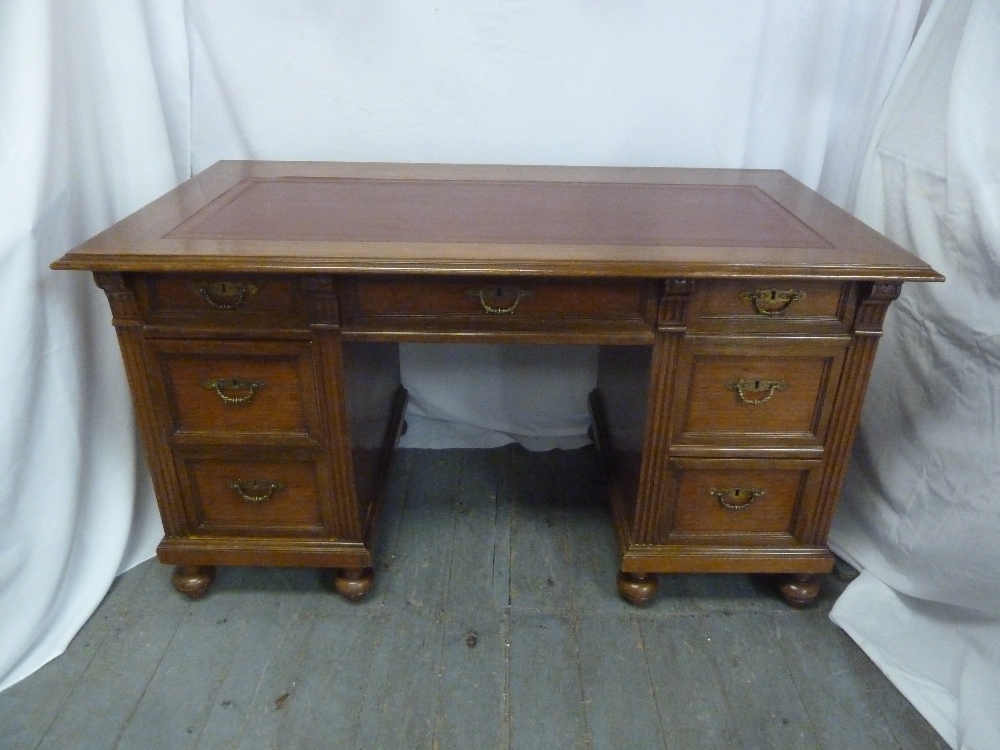 A rectangular mahogany partners desk with tooled leather top, the nine drawers with brass swing