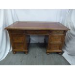 A rectangular mahogany partners desk with tooled leather top, the nine drawers with brass swing