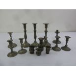 A quantity of pewter candlesticks, mugs and a jug of varying form and age
