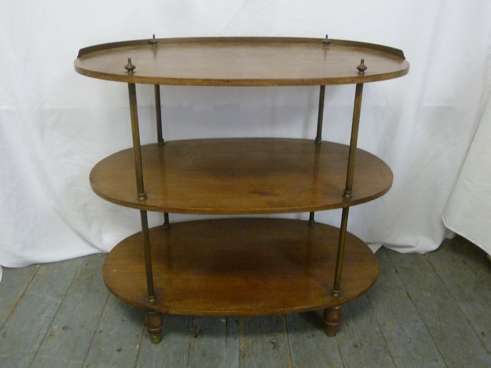 An oval three tier mahogany whatnot with brass gallery and supports