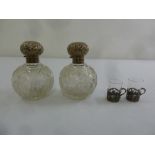 A pair of cut glass perfume bottles with silver covers and collars and a pair of shot glasses with