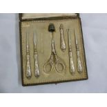 A cased white metal manicure set