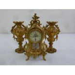 A French 19th century gilded metal mantle clock with porcelain panels and vase form garnitures