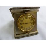 A silver engine turned 8 day travel clock shaped square with bar push clasp to hinged cover,