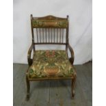 An Edwardian upholstered occasional chair with satinwood inlays and scroll legs on original castors