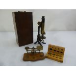 A Victorian brass microscope in fitted case and a brass postal scale with a cased set of weights