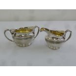 A George III silver sugar bowl and cream jug with basket weave band, gadrooned borders and serpent