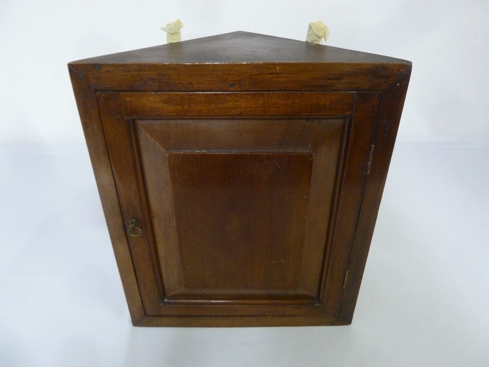 A Victorian mahogany wall mounted corner cabinet of moulded triangular section