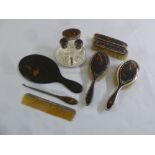A silver and tortoiseshell dressing table set to include brushes, a button hook and three bottles (