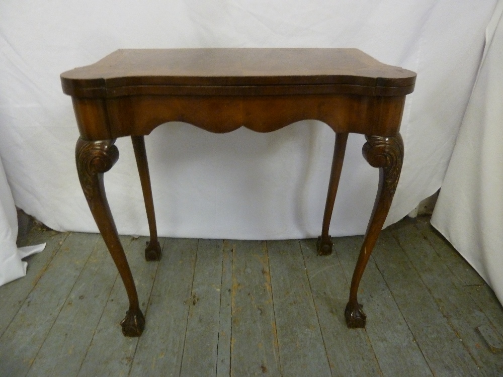 An early 20th century mahogany games table on four cabriole legs with ball and claw feet