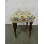 A mahogany upholstered stool on four turned tapering cylindrical legs