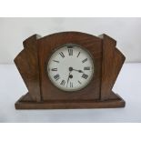 An Art Deco oak mantle clock with enamel dial and Roman numerals, single train movement