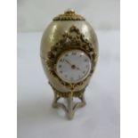 An engine turned silver Easter Egg desk clock with silver gilt mounts on integrated stand and