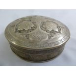 A Persian white metal circular box the pull off cover and sides profusely engraved with flowers,