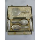 A cased set of silver mounted dressing table items to include a hand mirror, a pair of hair