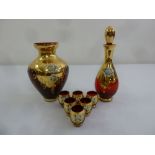 A set of mid 20th century ruby glass shot glasses with gold overlay and a matching decanter and
