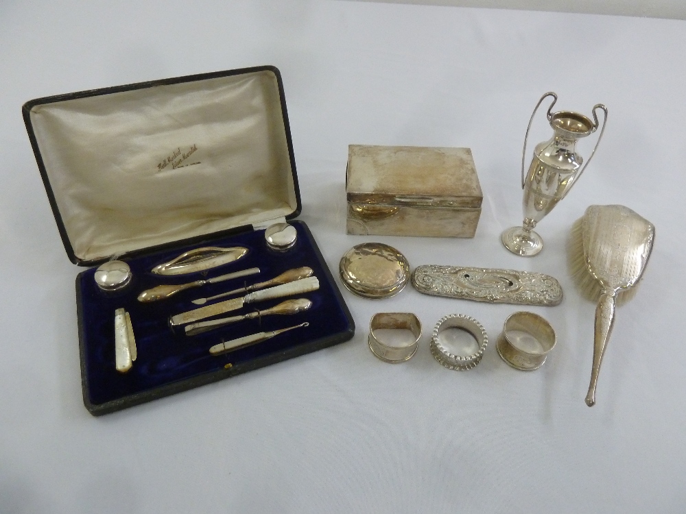 A quantity of silver to include a cased manicure set, a cigarette box and three napkin rings (9)