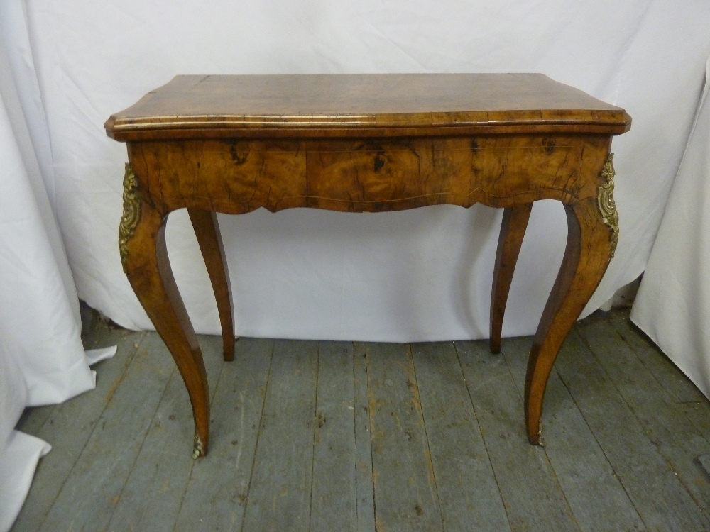 A Victorian walnut veneered games table on four cabriole legs with gilt metal mounts