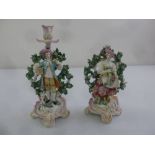 A pair of porcelain candlesticks in the form of two figures in 18th century costume, gold anchor