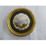 A circular hand painted porcelain panel depicting a lake scene in gilt wood frame