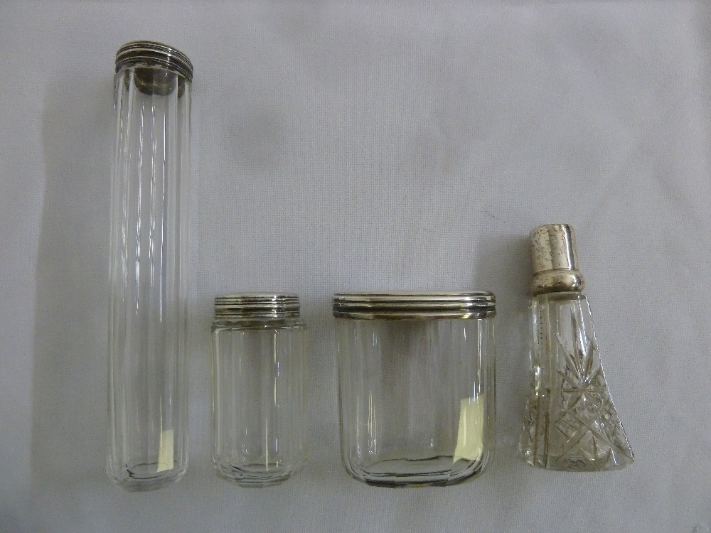 Four faceted glass dressing table bottles with silver covers