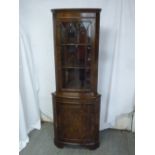 A walnut and mahogany corner cabinet with astral glazed top section above a cupboard on bracket