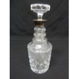 A cut glass decanter with drop stopper and silver collar