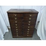 A rectangular oak filing cabinet made by Cooks of Finsbury with eighteen drawers and brass handles