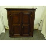 An oak barrel back corner cupboard with moulded hinged doors and brass handle, circa 1820