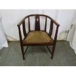 An early 20th century Arts and Crafts mahogany occasional chair with caned seat