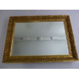 A rectangular gilded wooden bevelled edge wall mirror