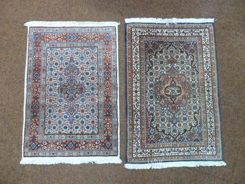 Two Middle Eastern prayer rugs with geometric repeating patterns in predominately red and blue